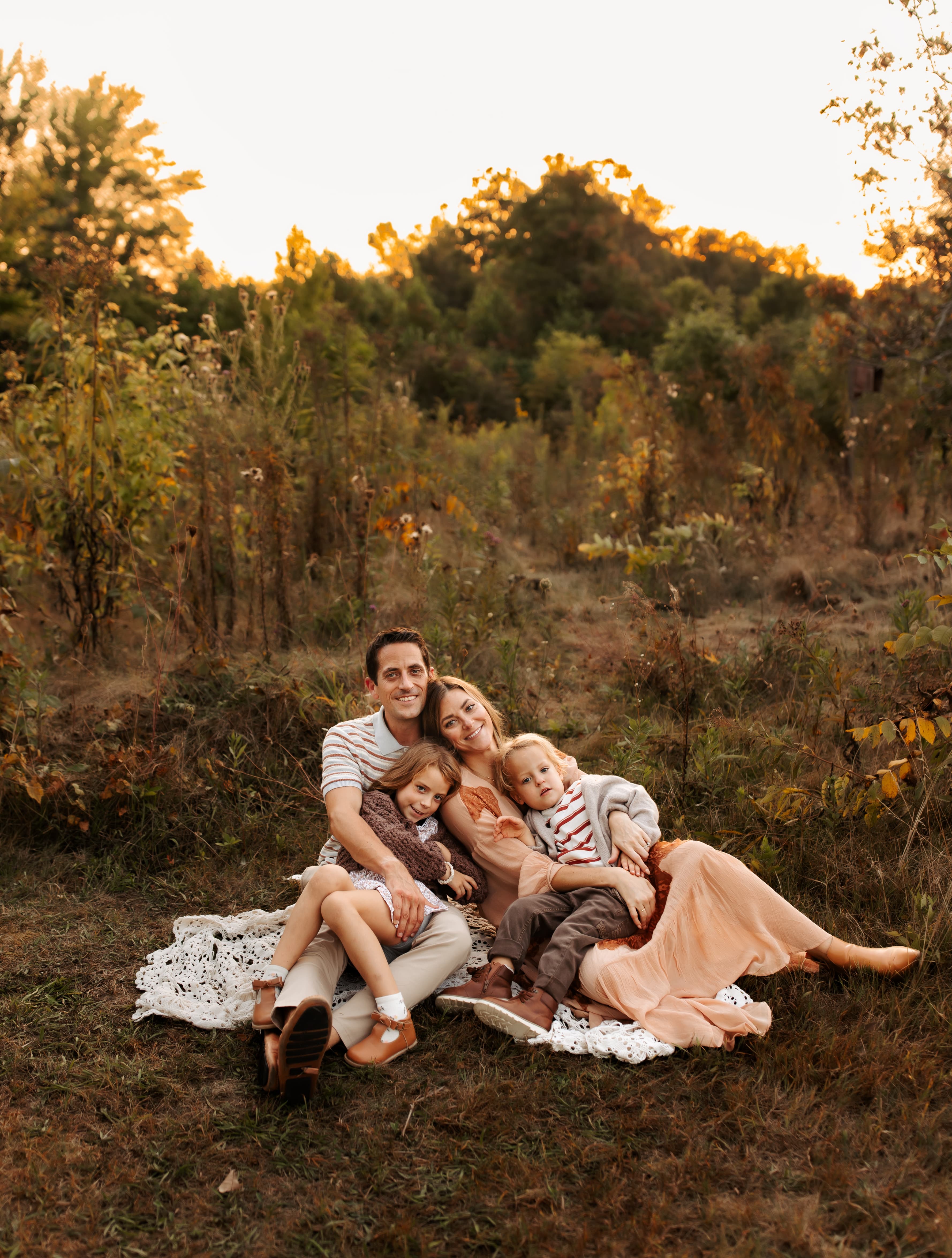 The founder's family sitting together in a field at golden hour